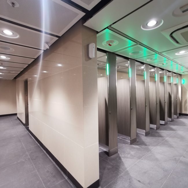 Toilet cubicles showing green light when unoccupied.