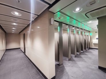 Toilet cubicles showing green light when unoccupied.