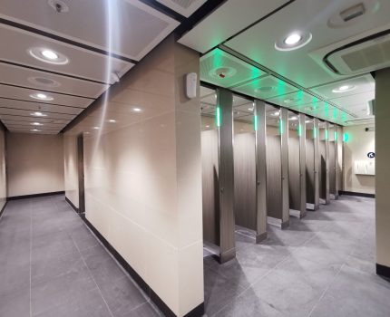 Toilet cubicles showing green light when unoccupied.