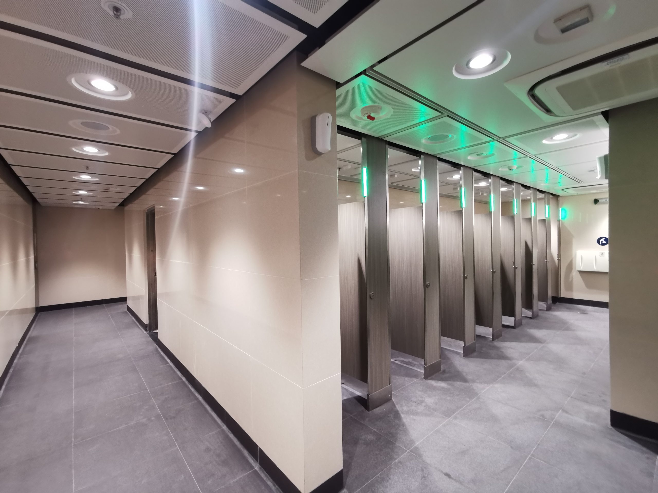 Toilet cubicles showing green light when unoccupied.